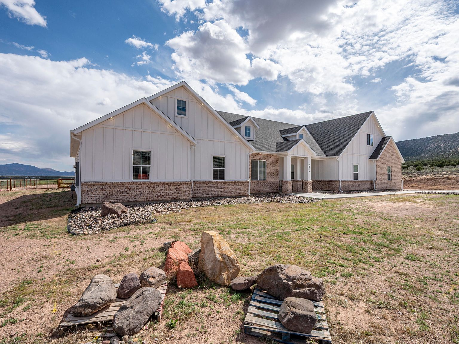 Side elevation of 7015 W 1300 N showing the full breadth of the home with the Cedar City foothills on the horizon and decorative boulders in the foreground