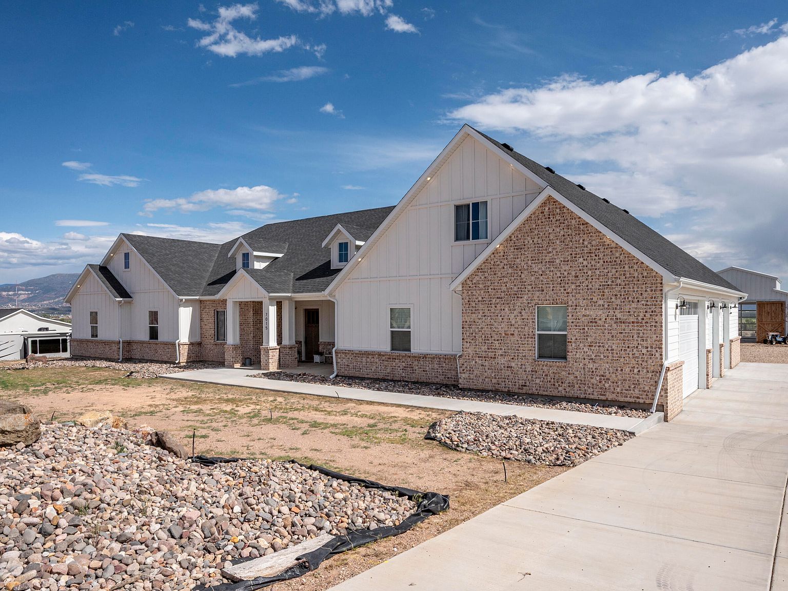 Three-quarter view from the driveway showing the garage wing of 7015 W 1300 N and the long valley view across to the mountains